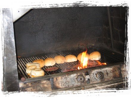 Burgers being grilled over hot charcoal